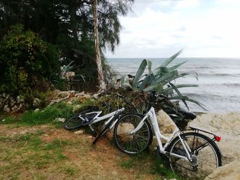 Bicycle on beach by sea against sky