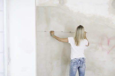 Rear view of woman measuring wall in yoga studio