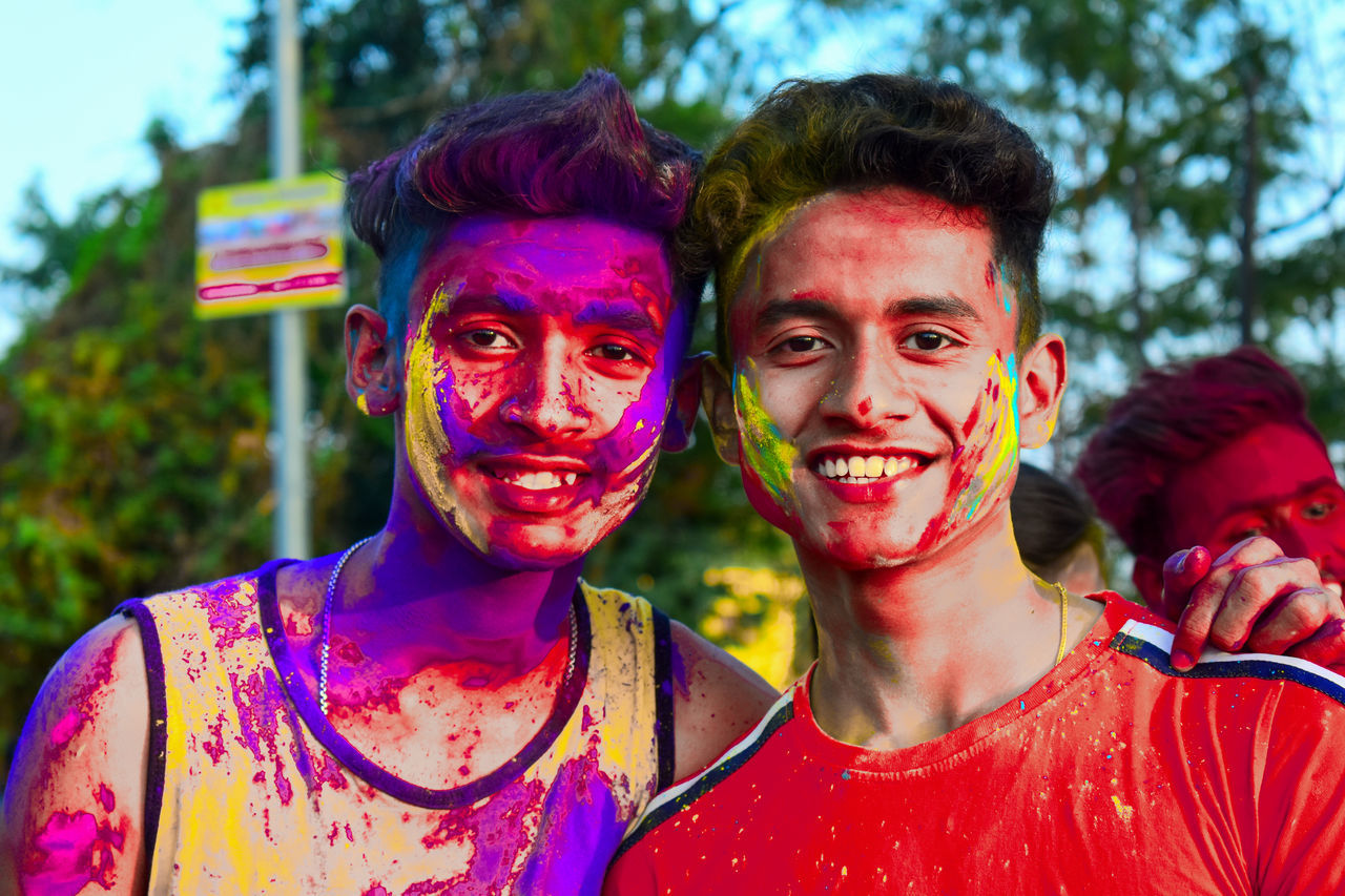 PORTRAIT OF SMILING YOUNG MAN WITH MULTI COLORED FACE