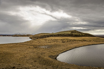 Dramatic cloudy sky over a landscape with grass, ponds, hills and lakes in myvatn region, iceland