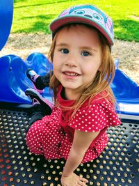 Portrait of smiling girl wearing cap while sitting outdoors
