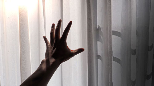 Cropped hand by curtain at home