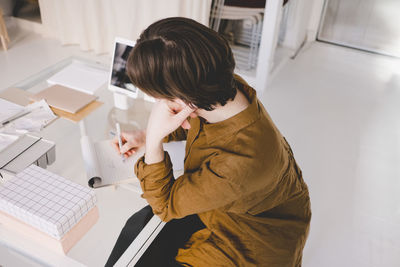 High angle view of young upholstery worker writing in note pad at store