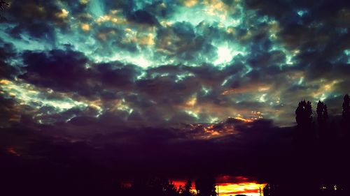 Low angle view of silhouette trees against cloudy sky