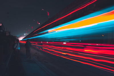 Man on illuminated road against sky at night