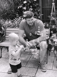 Full length of father and son sitting outdoors