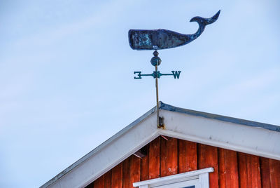 Low angle view of weather vane on house against clear sky