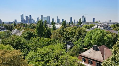 Trees and buildings in city against sky