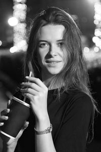 Portrait of beautiful woman holding camera at night