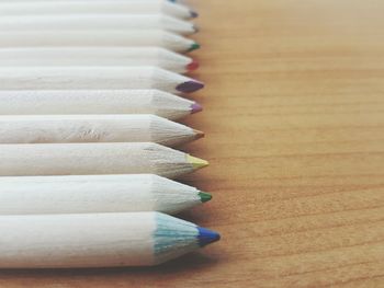 Close-up of colored pencils arranged in row on table