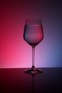 Close-up of wineglass on table against red background