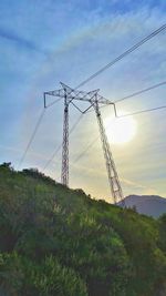 Low angle view of electricity pylon on field