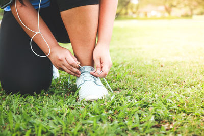 Low section of woman wearing shoes on field