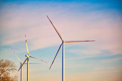 Low angle view of wind turbine against sky during sunset