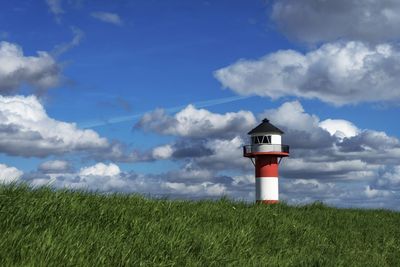 Lighthouse on field against sky