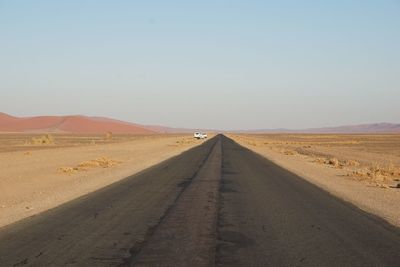 Road amidst desert against clear sky