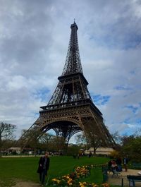 People in park by eiffel tower against sky