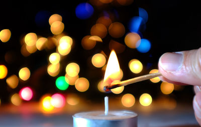 Close-up of hand holding illuminated candle