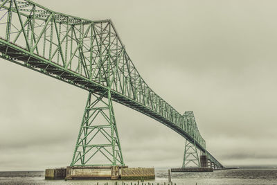 Low angle view of bridge over sea against cloudy sky during sunset