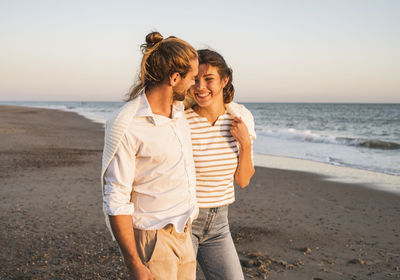 Friends standing at beach against sky