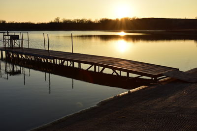 Pier over lake against sky during sunset