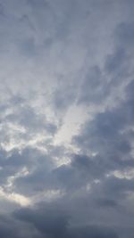 Low angle view of sunlight streaming through clouds