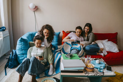 Young female friends using mobile phones at home