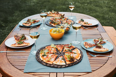 Family and friends having meal - pizza, salads, fruits and drinking white wine during summer picnic