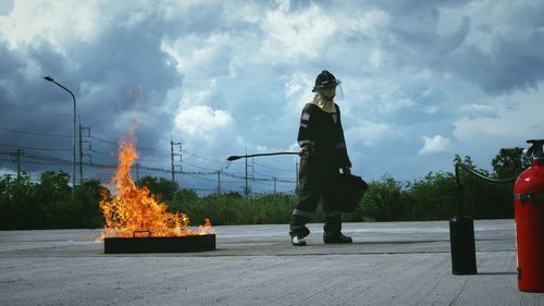 Full length of firefighter standing on road against sky