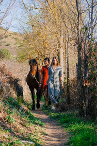 Full length of women walking with horse outdoors