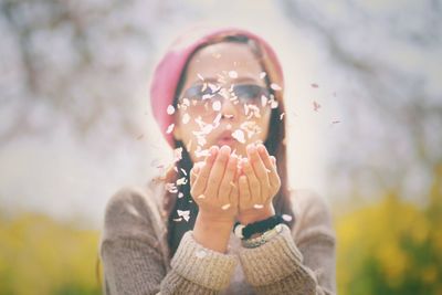 Woman blowing flower petals in hand