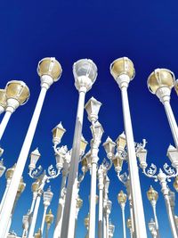 Low angle view of lighting equipment against blue sky on sunny day