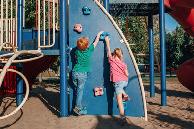 Rear view of siblings playing in playground