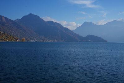 Scenic view of sea by mountains against sky