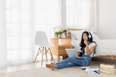 Young woman using mobile phone while sitting on table