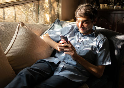 Man using mobile phone while sitting on sofa