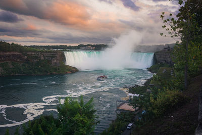 Scenic view of niagara falls against cloudy sky during sunset