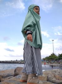 Woman standing at beach against sky