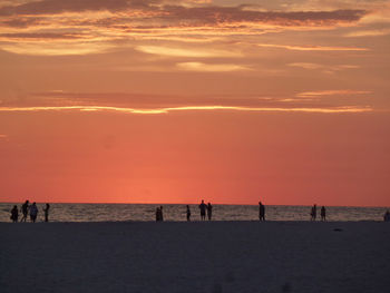 Silhouette people on beach against sky during sunset