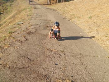 Full length of girl sitting on road