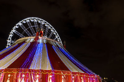 Low angle view of illuminated ferris wheel against sky at night