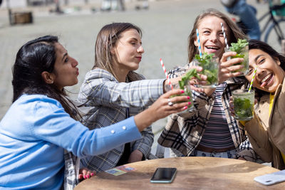 Smiling friends toasting drinks at restaurant