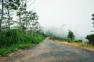 Road amidst field against clear sky