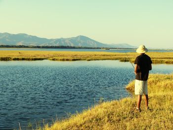 Rear view of woman standing on lake against clear sky