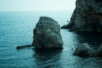 Rock formation in sea against clear sky