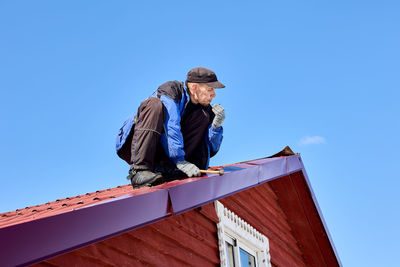 Low angle view of man standing against clear blue sky