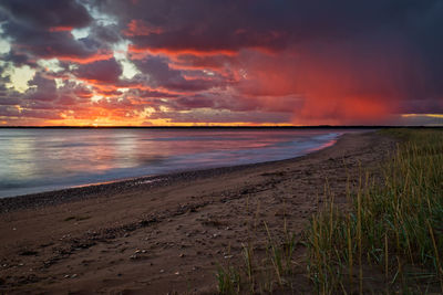 Scenic view of sea against dramatic sky during sunset