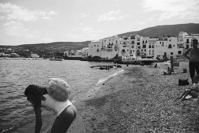 Rear view of woman on beach against sky in city