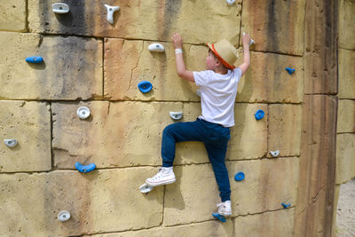 The boy is engaged in rock climbing.