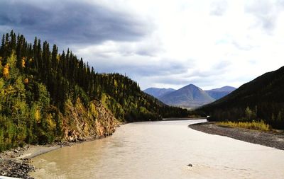 Scenic view of river by mountains against sky